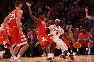 St. John's Durand Johnson dribbles around Tyler Roberson with his hands extended high on defense.