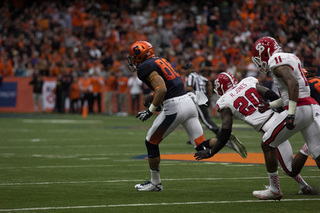 SU wide receiver Jarrod West, a big-play weapon for the Orange's offense, heads downfield after making a reception as NCSU safety Hakim Jones pursues him.