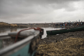 Water protectors wait along the right bank of the river to peacefully travel across to say communal prayers Thanksgiving Day.