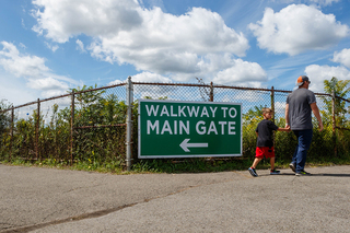 Two fairgoers walk away from the sign to the main gate of the fair.