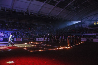 The evening's riders line up along the fading flames in the arena.