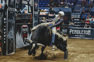 Ouncie Mitchell clings to the bull rope, keeping him mounted on the bull.