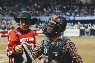 Alex Jenks retrieves his bull rope as he watches the replay of his ride.