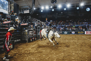 Joe Hostetler grips onto his bull rope as his bull launches out of the bucking chute.