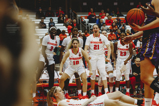 Multiple bench players cheer an Orange defender taking a charge. 