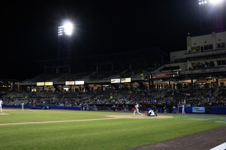 Lights shine down bright upon the players as the Mets take to the outfield. 